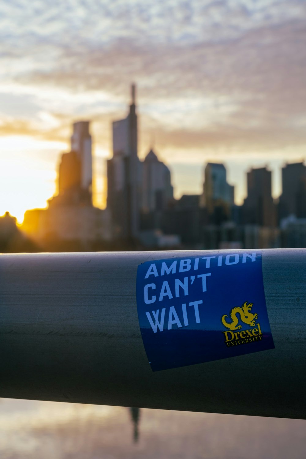 a blue sticker on a metal rail in front of a city skyline
