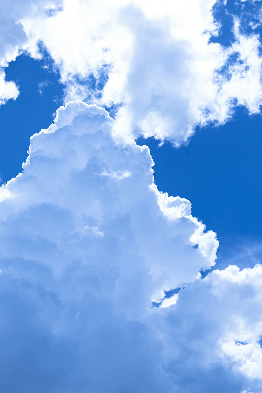 a plane flying through a cloudy blue sky