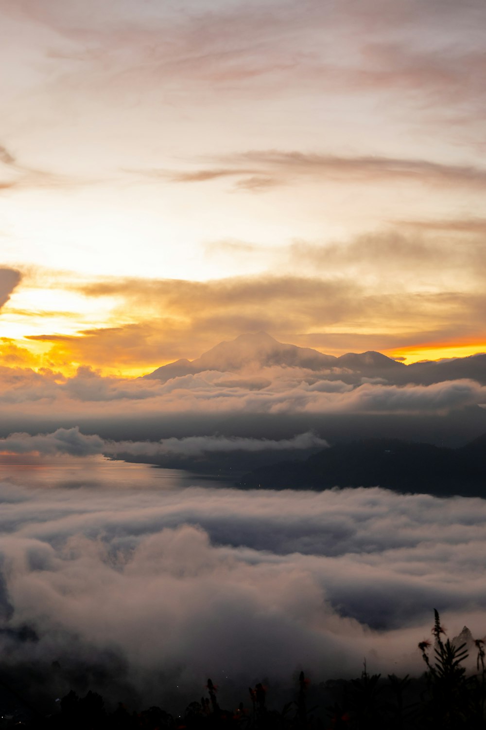 the sun is setting over the clouds in the mountains