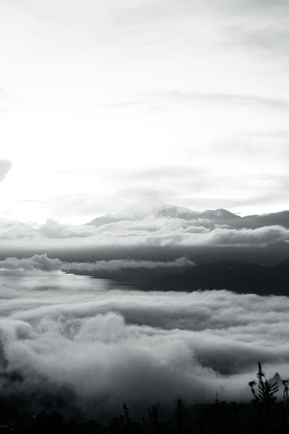 a black and white photo of clouds and mountains