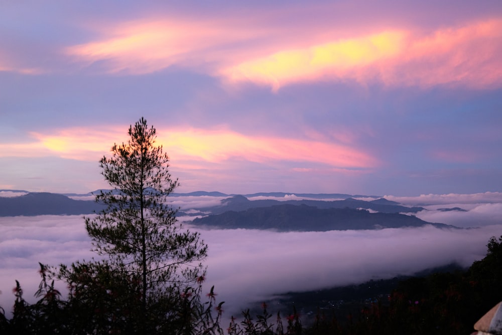 a view of the clouds and mountains from a hill