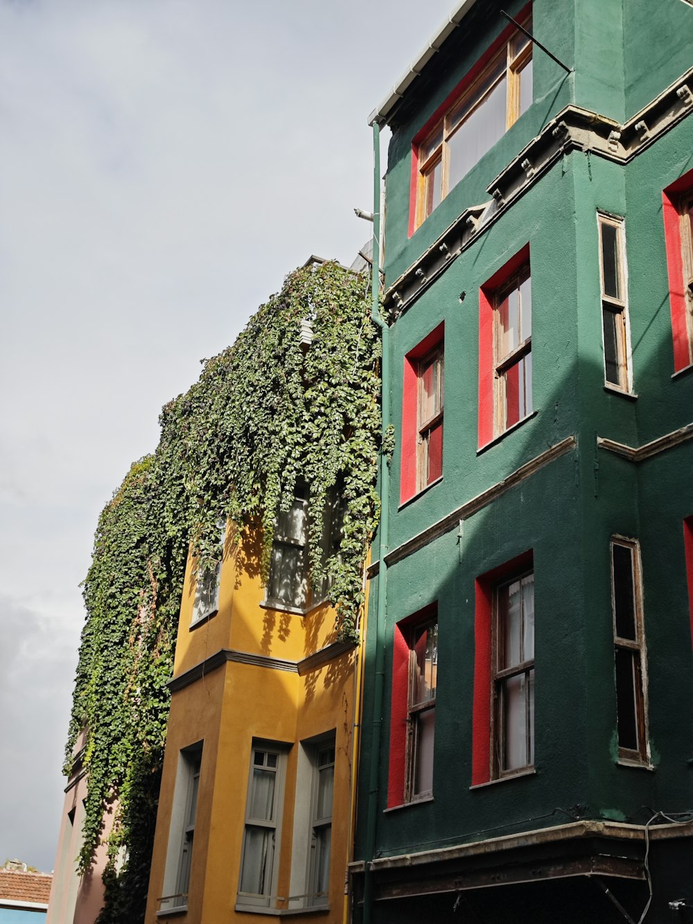 a green building with red shutters next to a yellow building