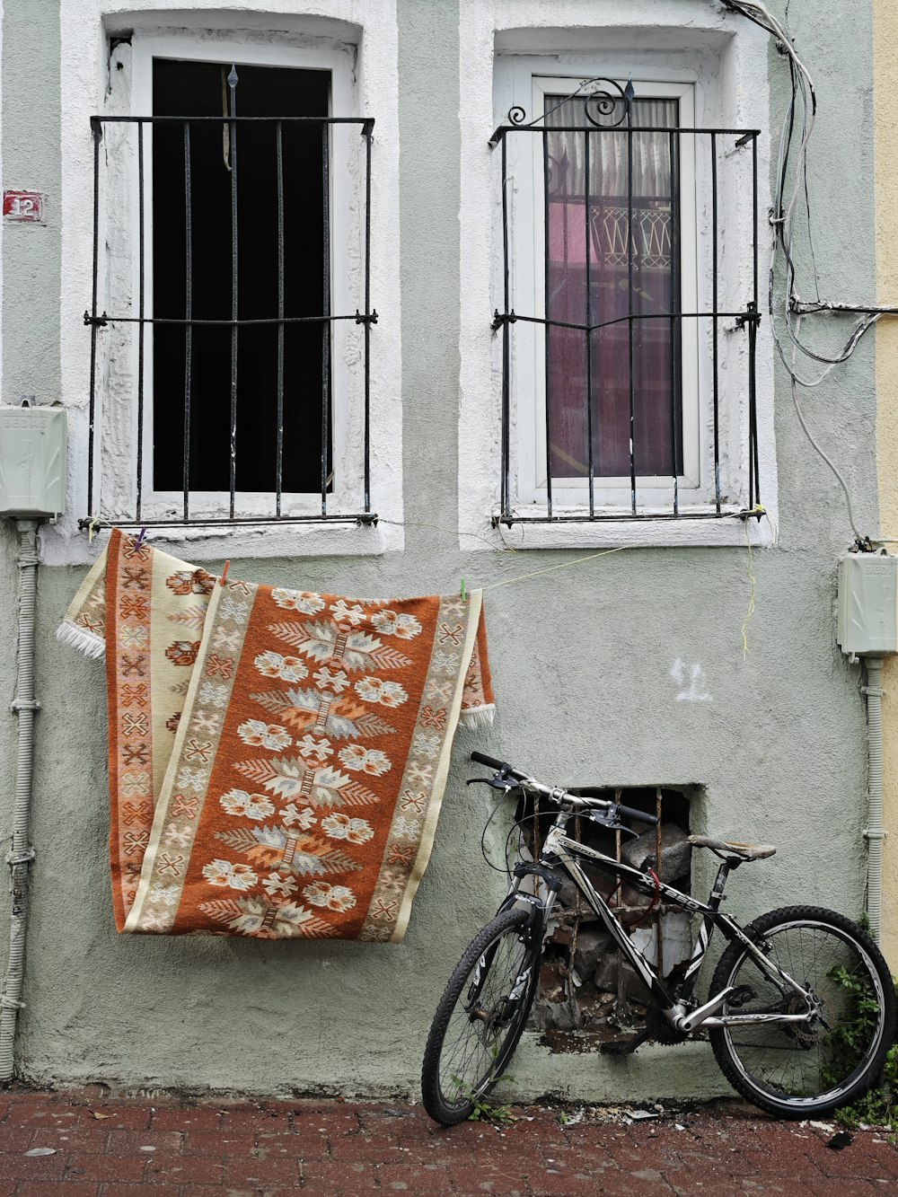 a bicycle parked next to a building with a rug on it