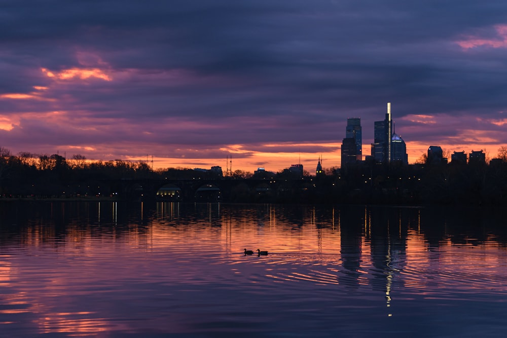 a beautiful sunset over a lake with a city in the background