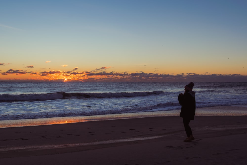 a person standing on a beach at sunset