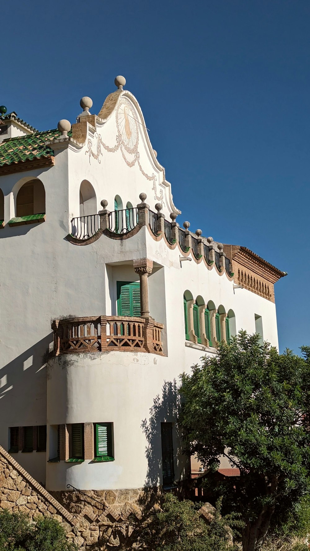 Un edificio blanco con persianas verdes y un balcón