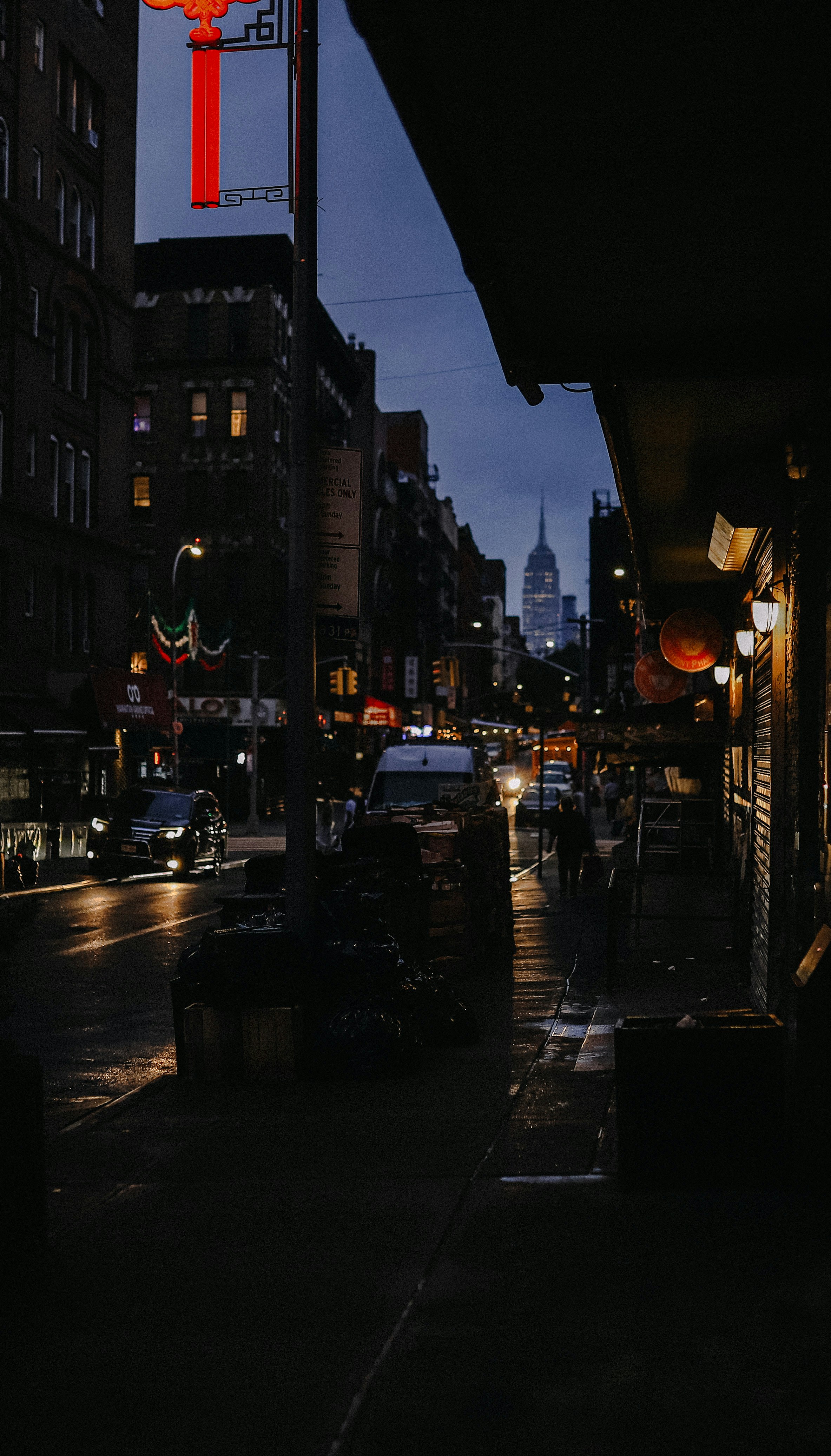 a city street at night with a tall building in the background