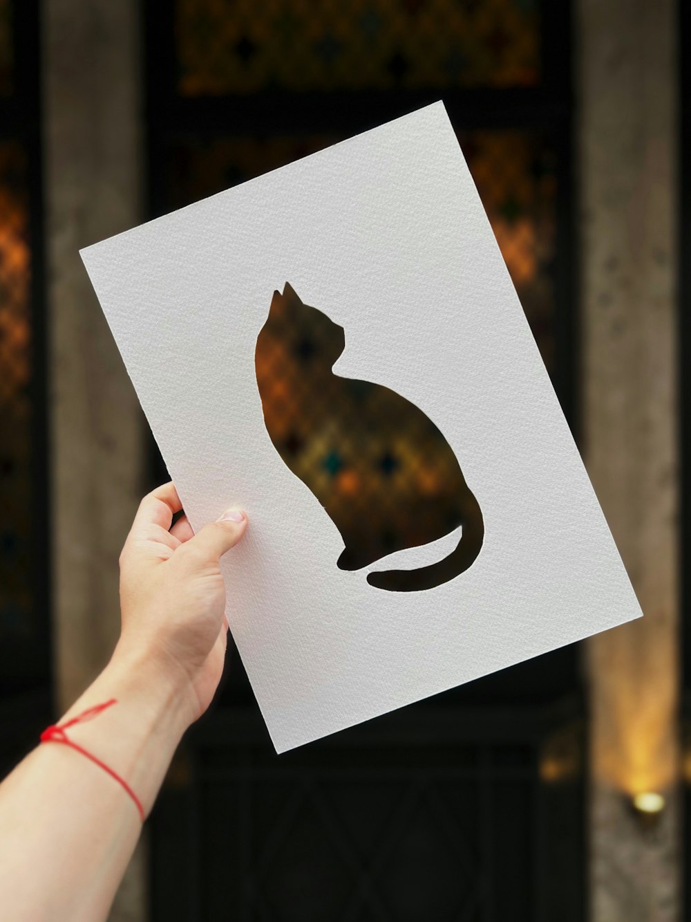 a person holding up a piece of paper with a cat on it