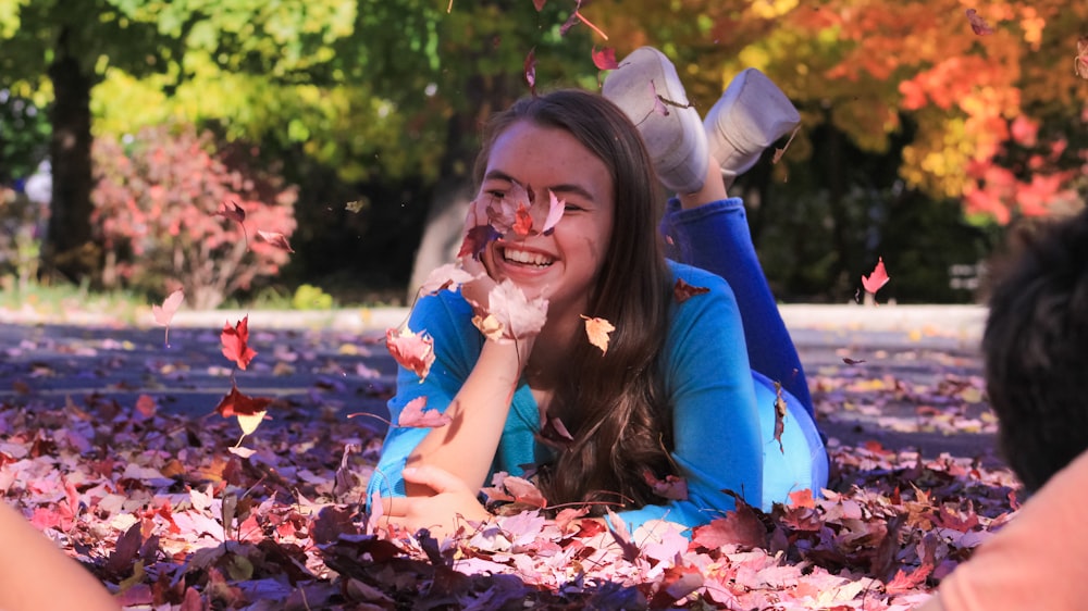 a woman laying on the ground surrounded by leaves