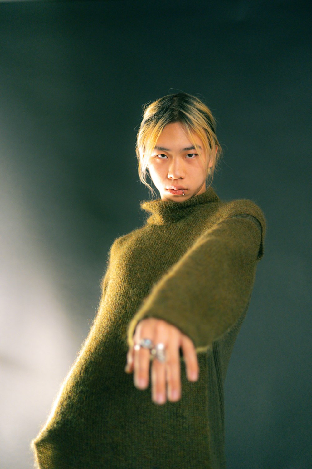 a woman in a green sweater pointing at the camera