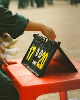 A hand is adjusting the numbers on a scoreboard, which displays the scores 17 and 20. The scoreboard is placed on a red plastic table. The focus is on the hand and the numbers, with a blurred background.