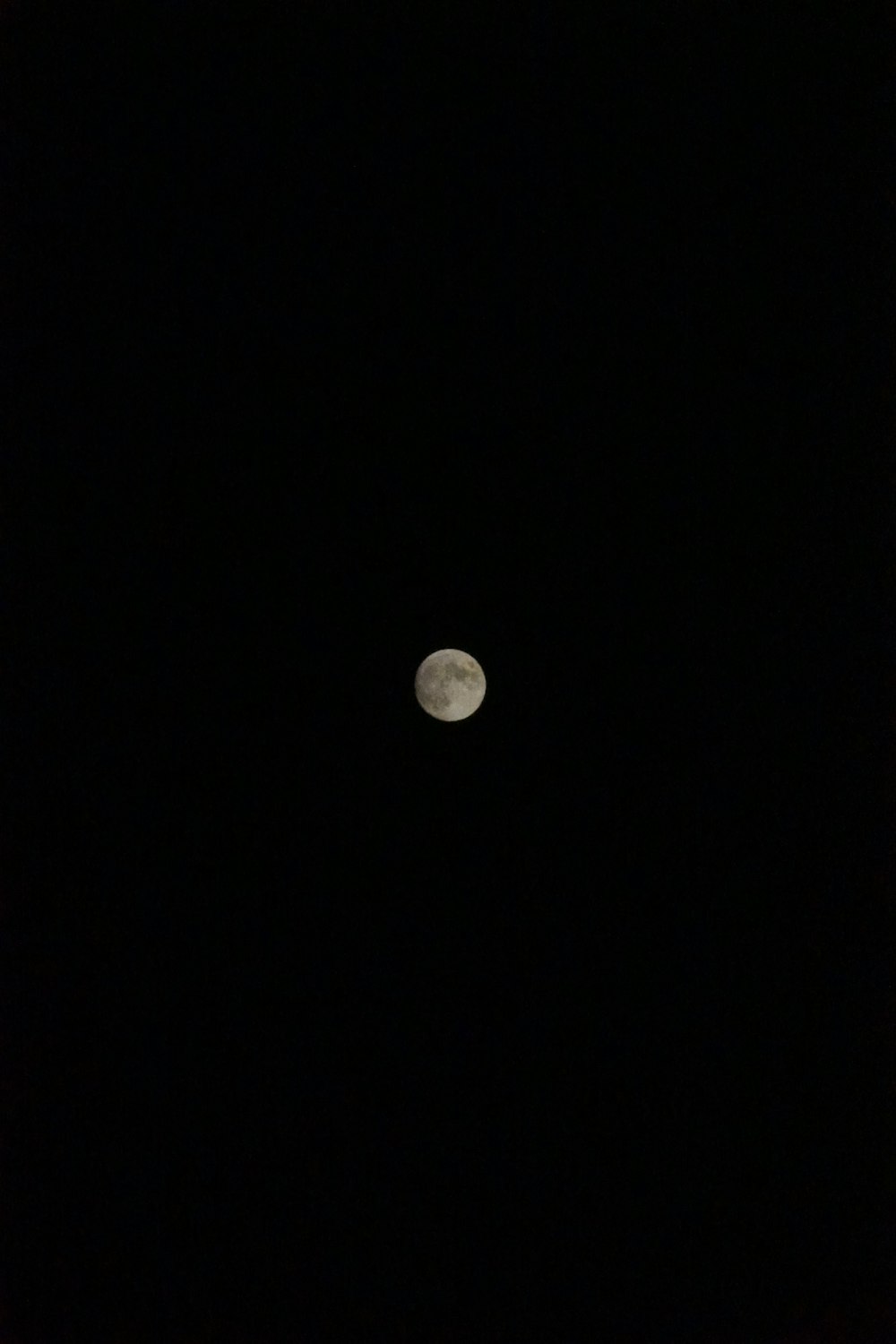 Une pleine lune est vue dans le ciel sombre