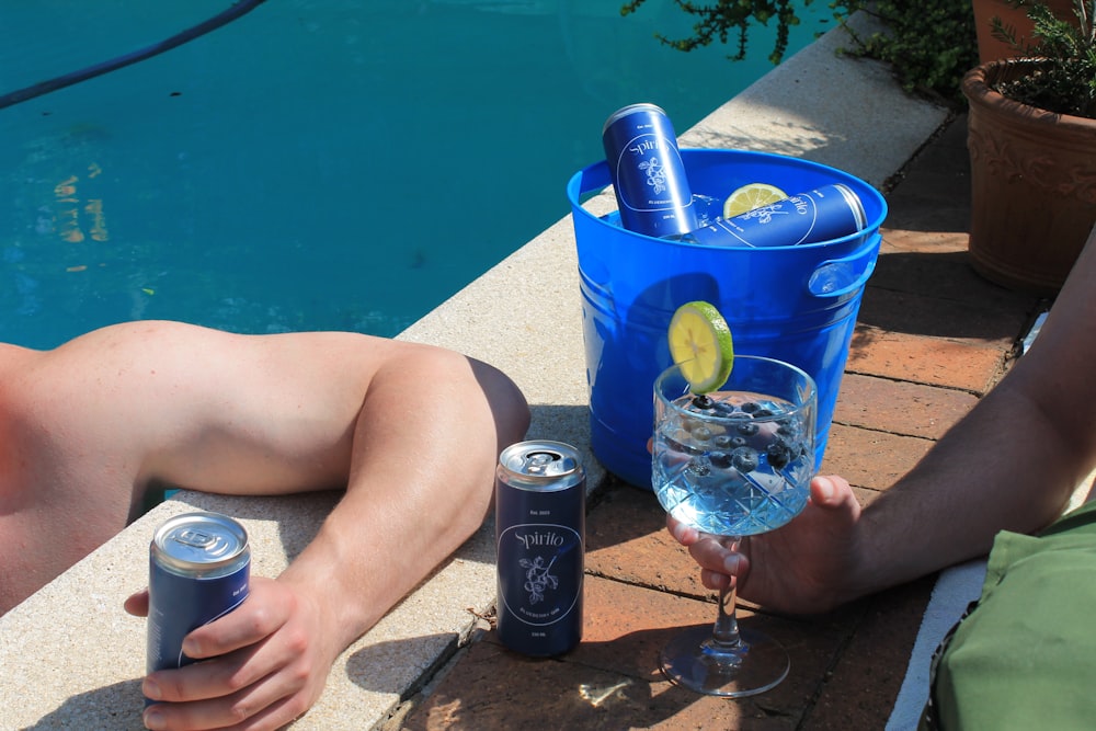 a man sitting next to a pool holding a glass of water