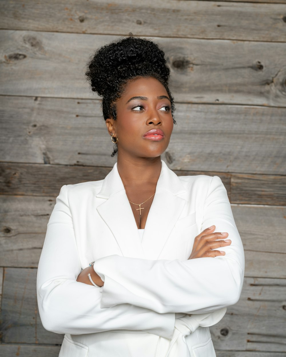 a woman in a white suit standing with her arms crossed