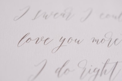 Elegant handwritten script in a soft, flowing style, featuring phrases like 'love you more' on a textured, white background.