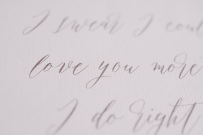 Elegant handwritten script in a soft, flowing style, featuring phrases like 'love you more' on a textured, white background.