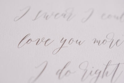 Elegant handwritten script in a soft, flowing style, featuring phrases like 'love you more' on a textured, white background.