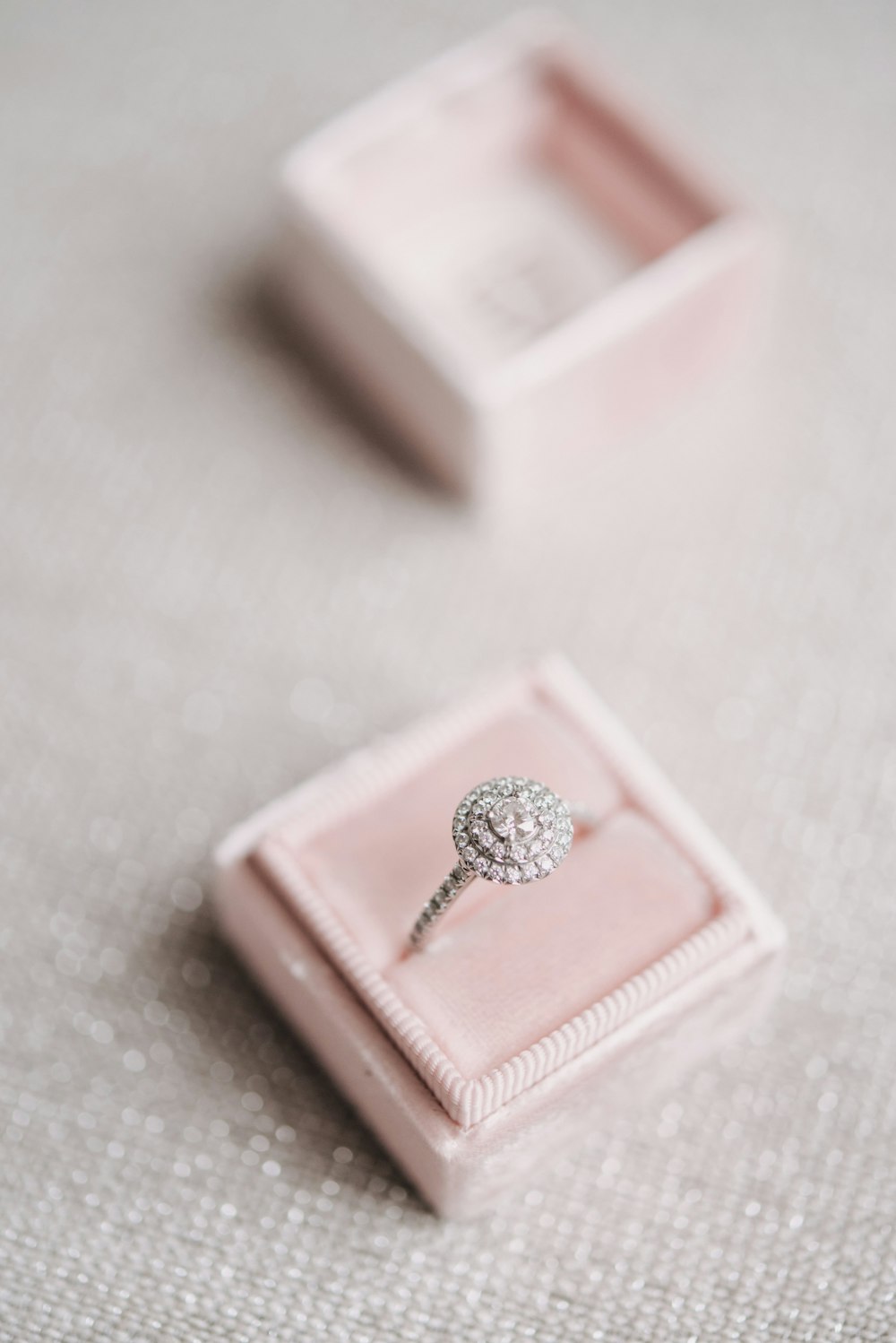 a diamond ring sits in a pink velvet box