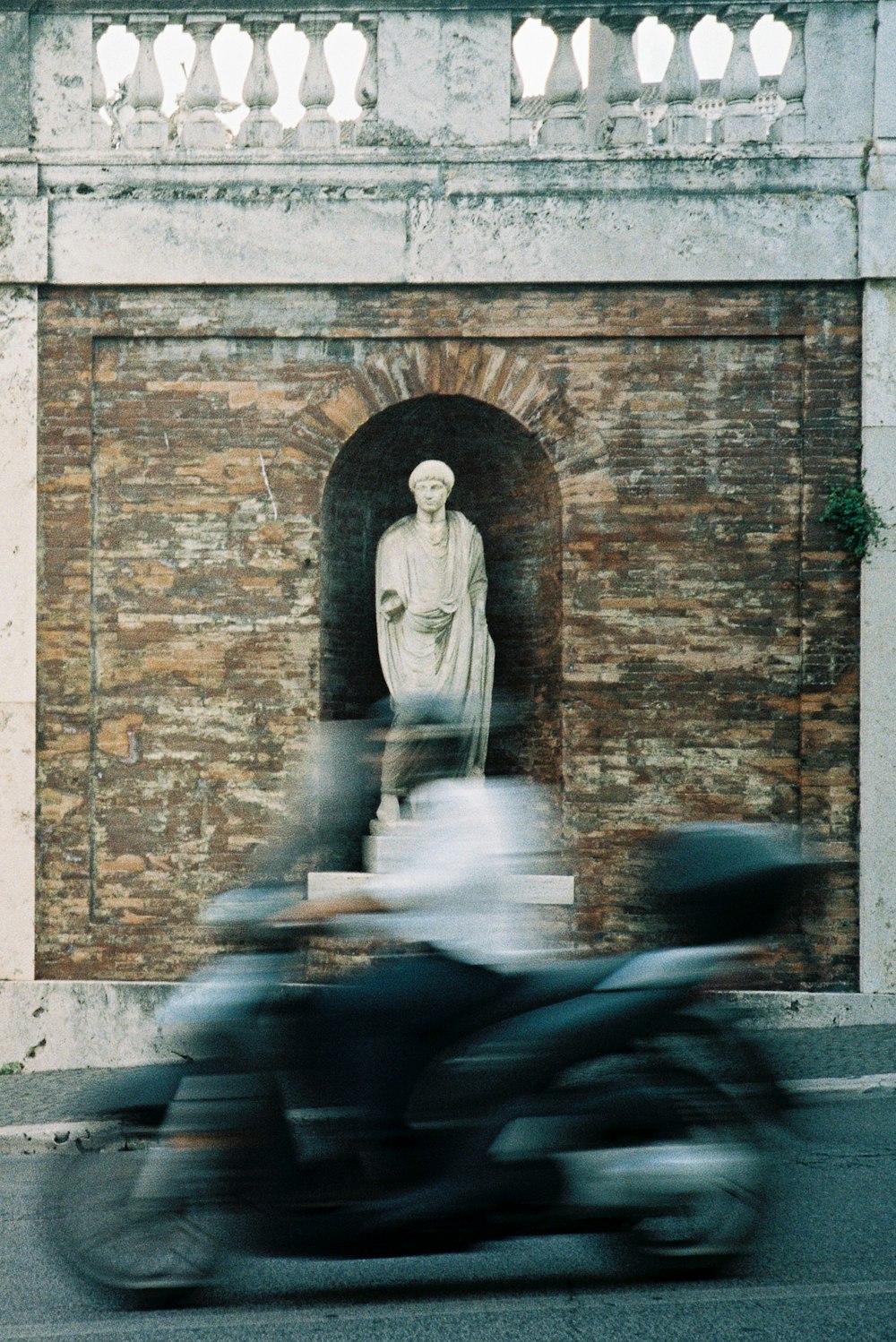 a blurry photo of a motorcycle passing by a statue