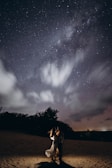 A couple holding hands under a starlit sky, symbolizing reunion and hope