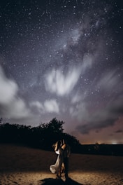 A couple holding hands under a starry sky, symbolizing love and connection.
