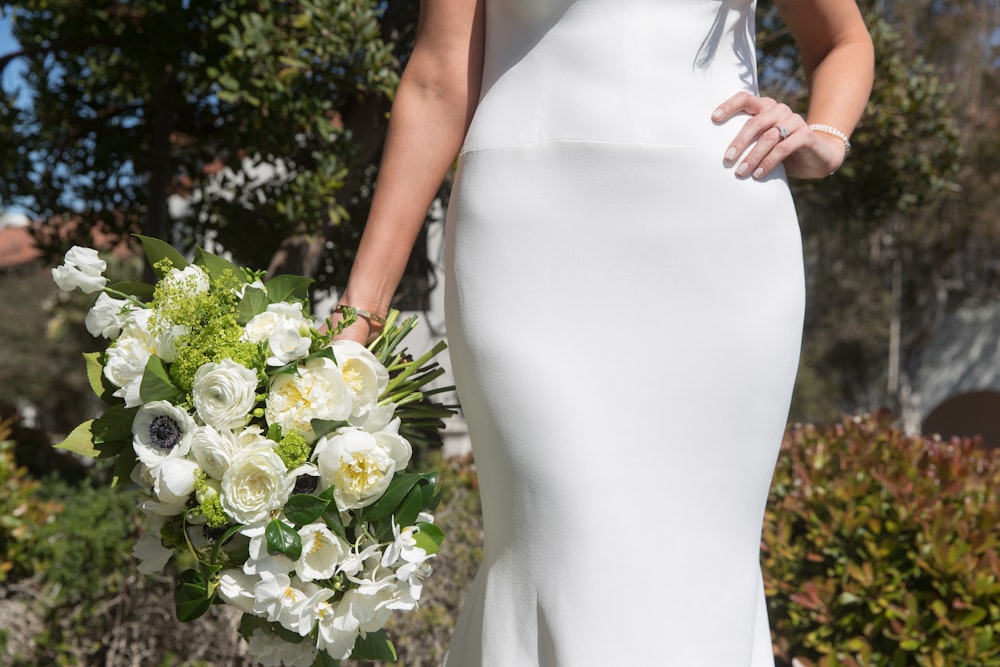 a woman in a white dress holding a bouquet of flowers