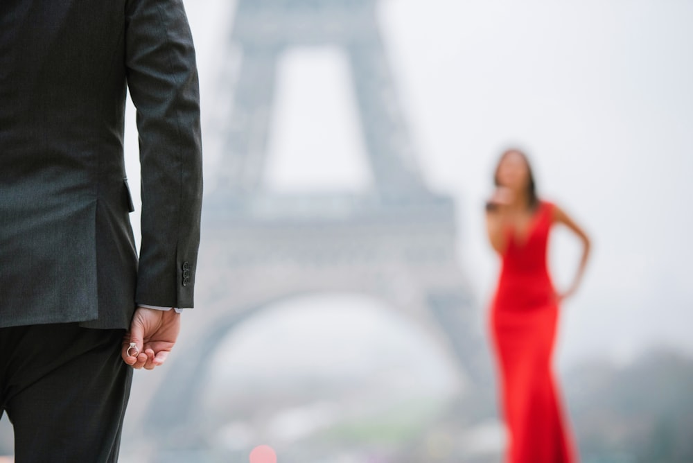 Um homem e uma mulher de mãos dadas em frente à Torre Eiffel