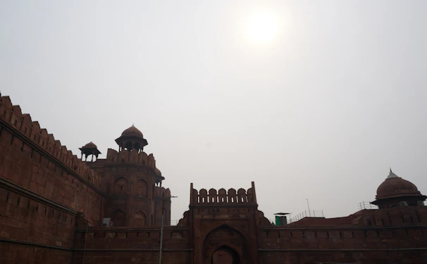 Historic Red Fort walls bathed in golden morning light with tourists nearby.