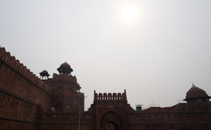 The imposing red sandstone walls of the Red Fort under a clear blue sky.
