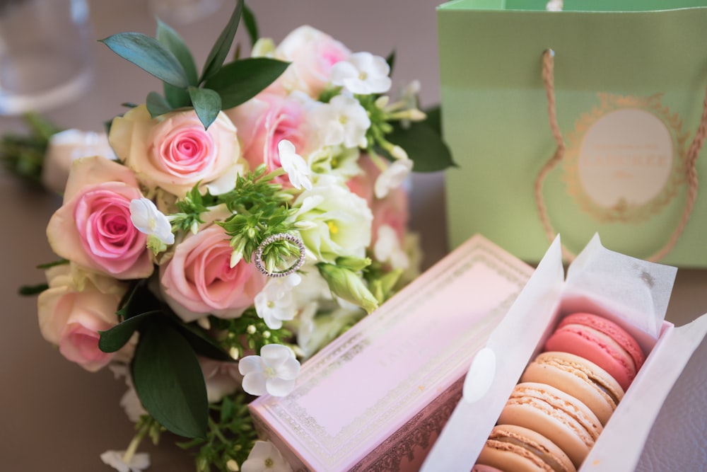 a box of macaroons sitting next to a bouquet of flowers