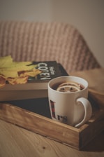 a cup of coffee and a book on a tray