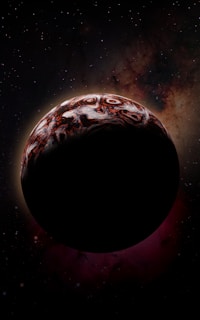A dark celestial body, possibly a planet or moon, is silhouetted against a backdrop of deep space, with swirling patterns of red and white on its surface. The background features a dense star field and nebulous clouds with a mix of dark and light hues.