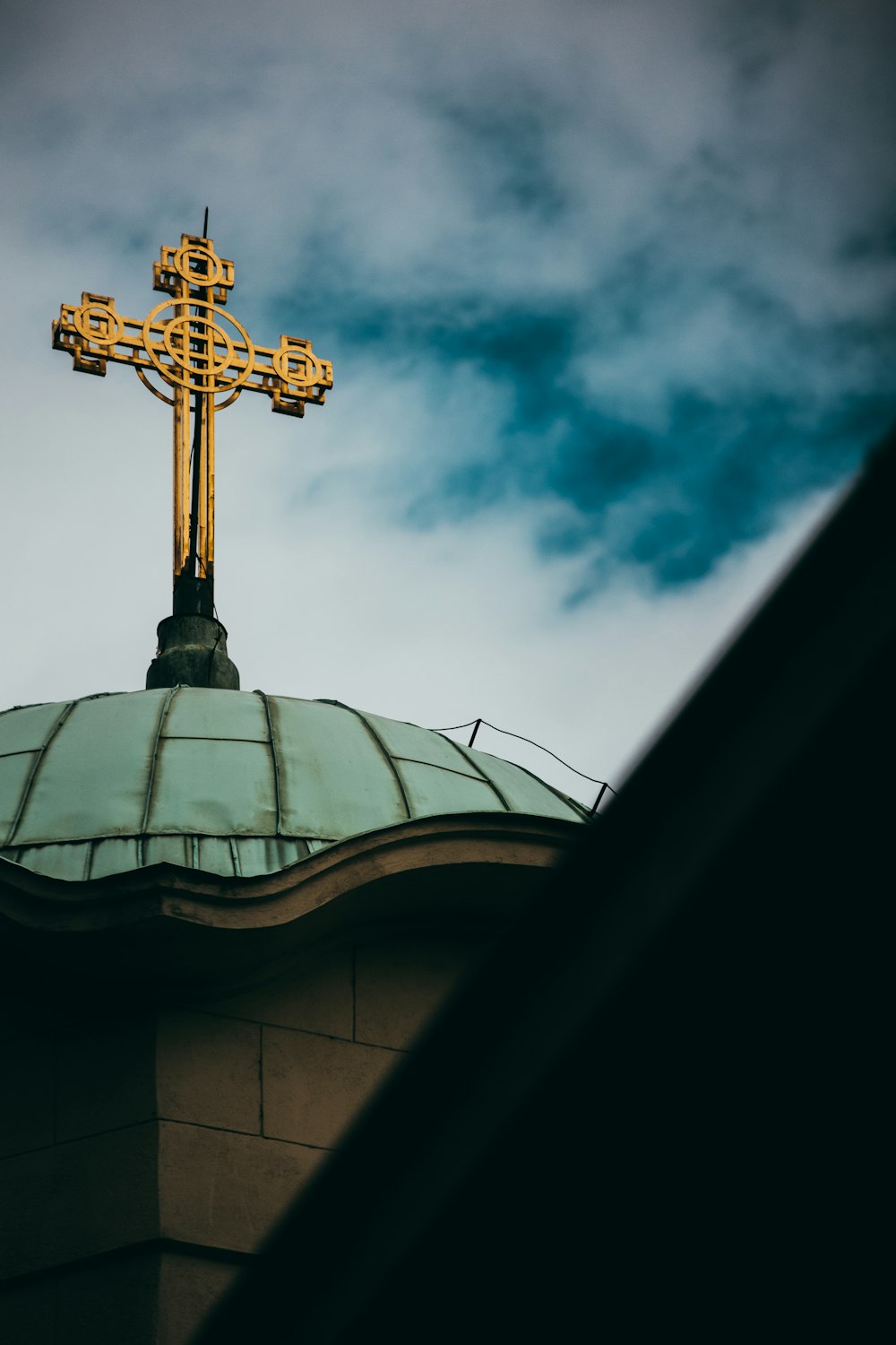 a cross on top of a building with a sky background