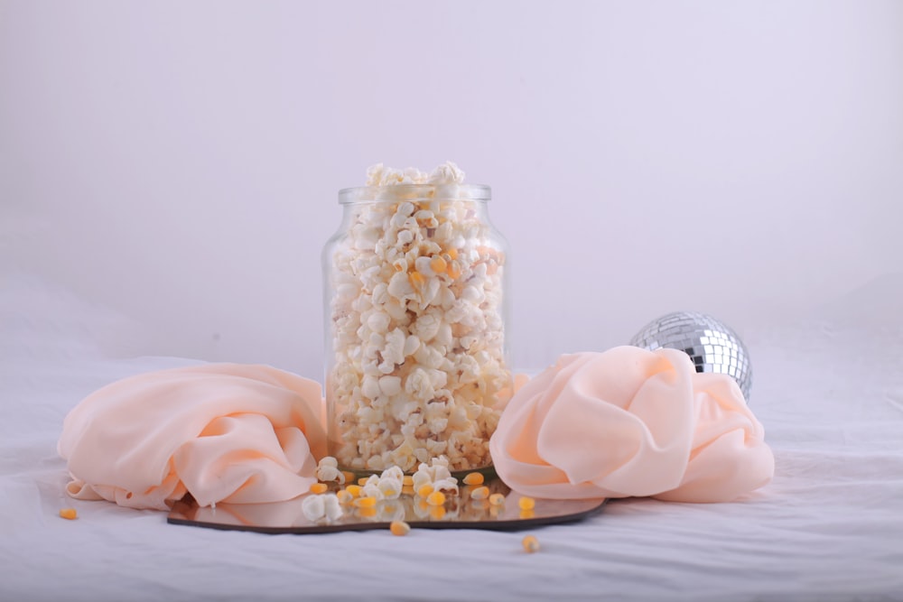 a jar filled with popcorn next to a spoon