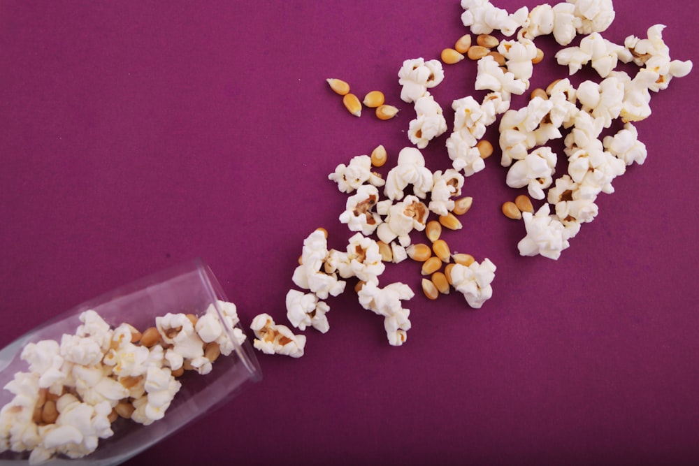 a bowl of popcorn spilled on a purple surface
