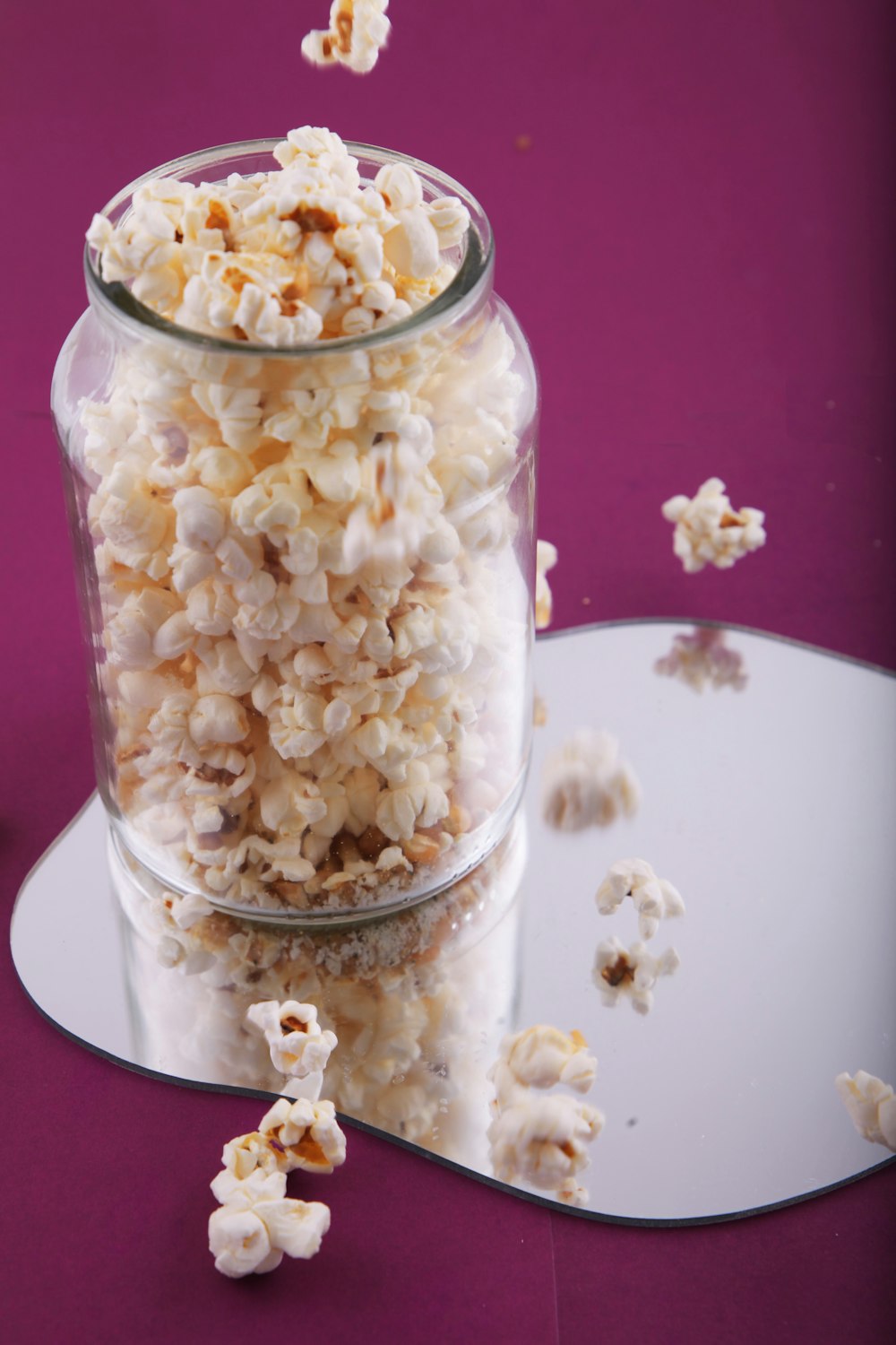 a glass jar filled with popcorn on top of a table