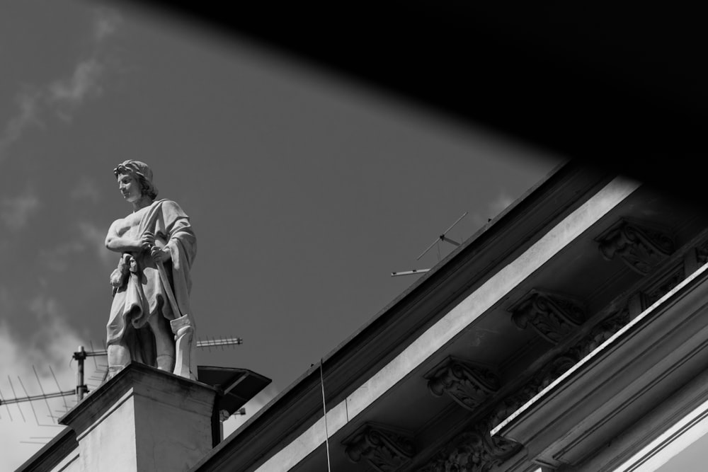 a black and white photo of a statue on top of a building