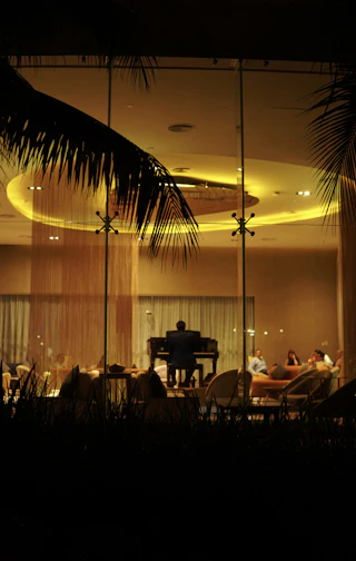 A softly lit hotel lounge with a pianist playing an elegant melody, bathed in warm gold tones.