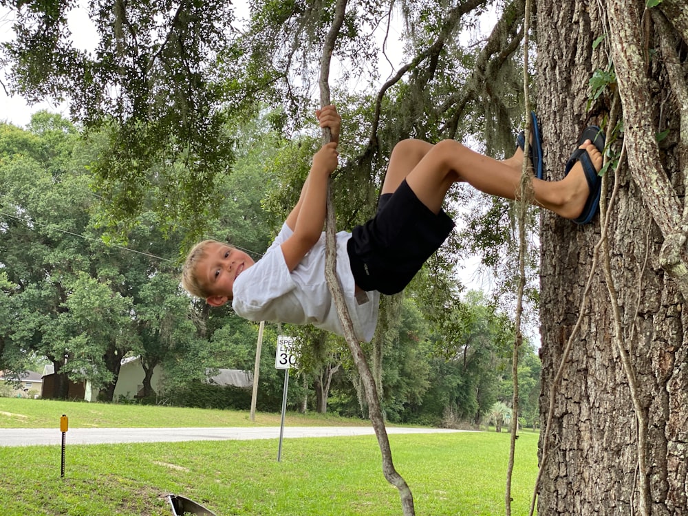 a young boy climbing up a tree in a park