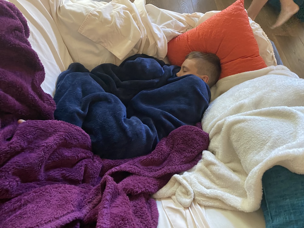 a man sleeping on a bed covered in blankets