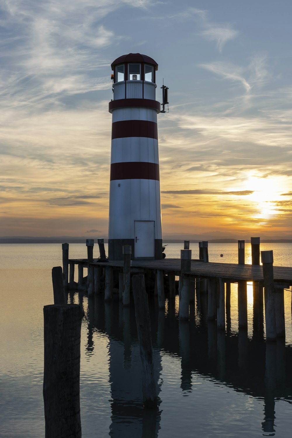 a red and white lighthouse sitting on top of a pier