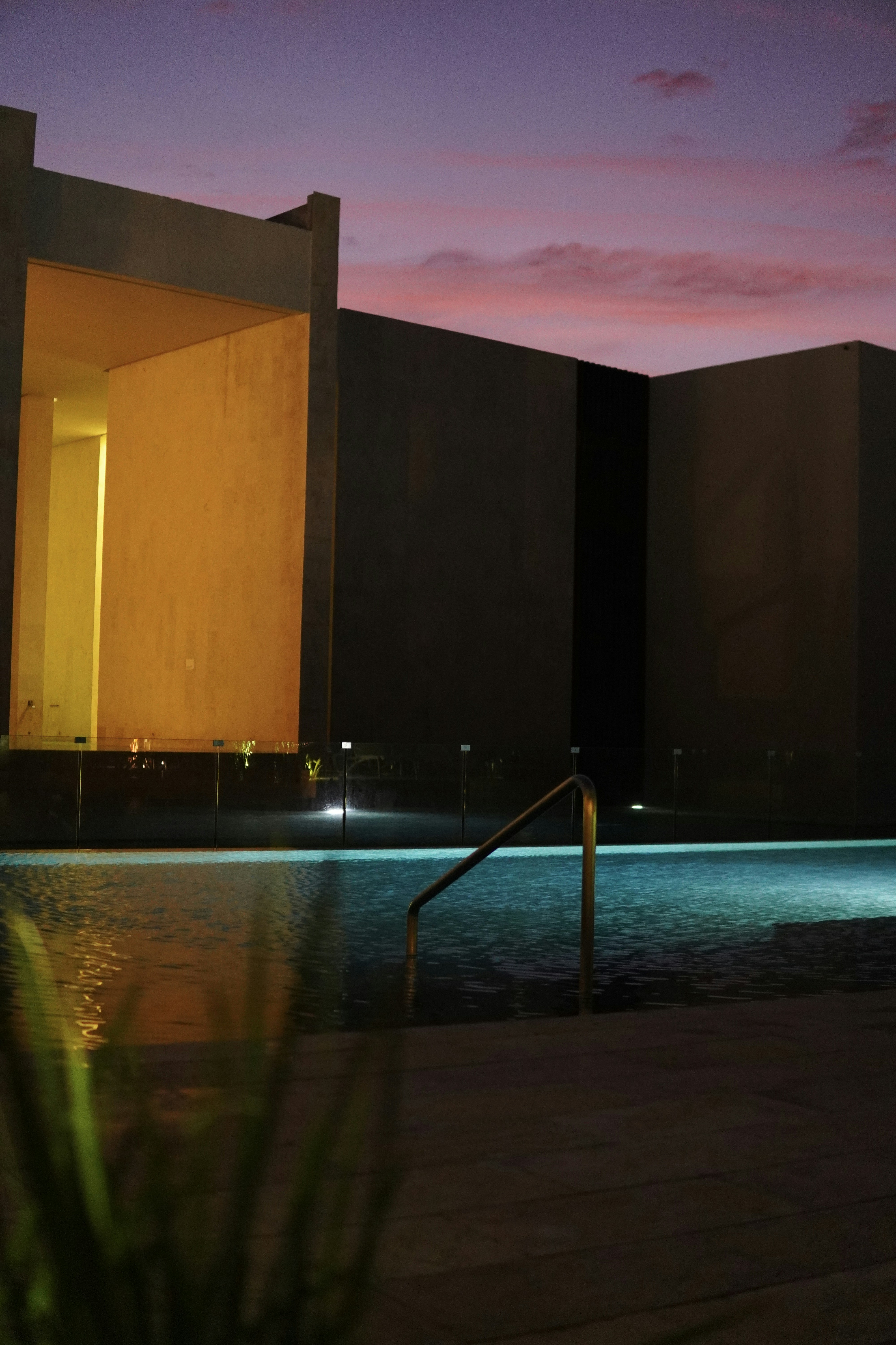 Grand modern estate with sweeping hillside views, dramatic cantilever architecture, infinity pool, warm dusk lighting, shadowed foreground landscaping