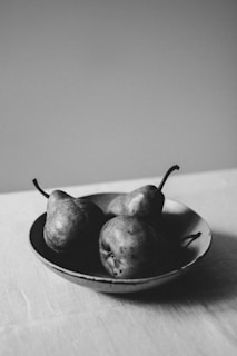 three pears in a bowl on a table