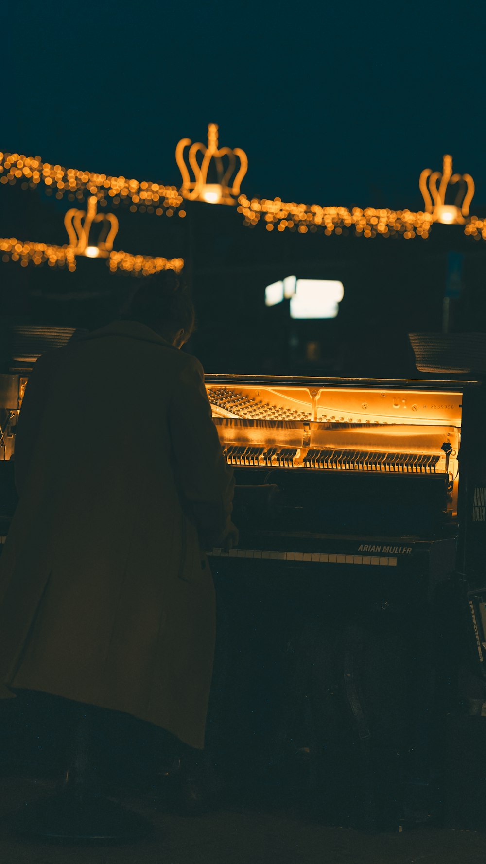 uma pessoa sentada em um piano na frente de algumas luzes