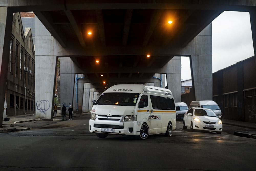 a white van driving down a street under a bridge