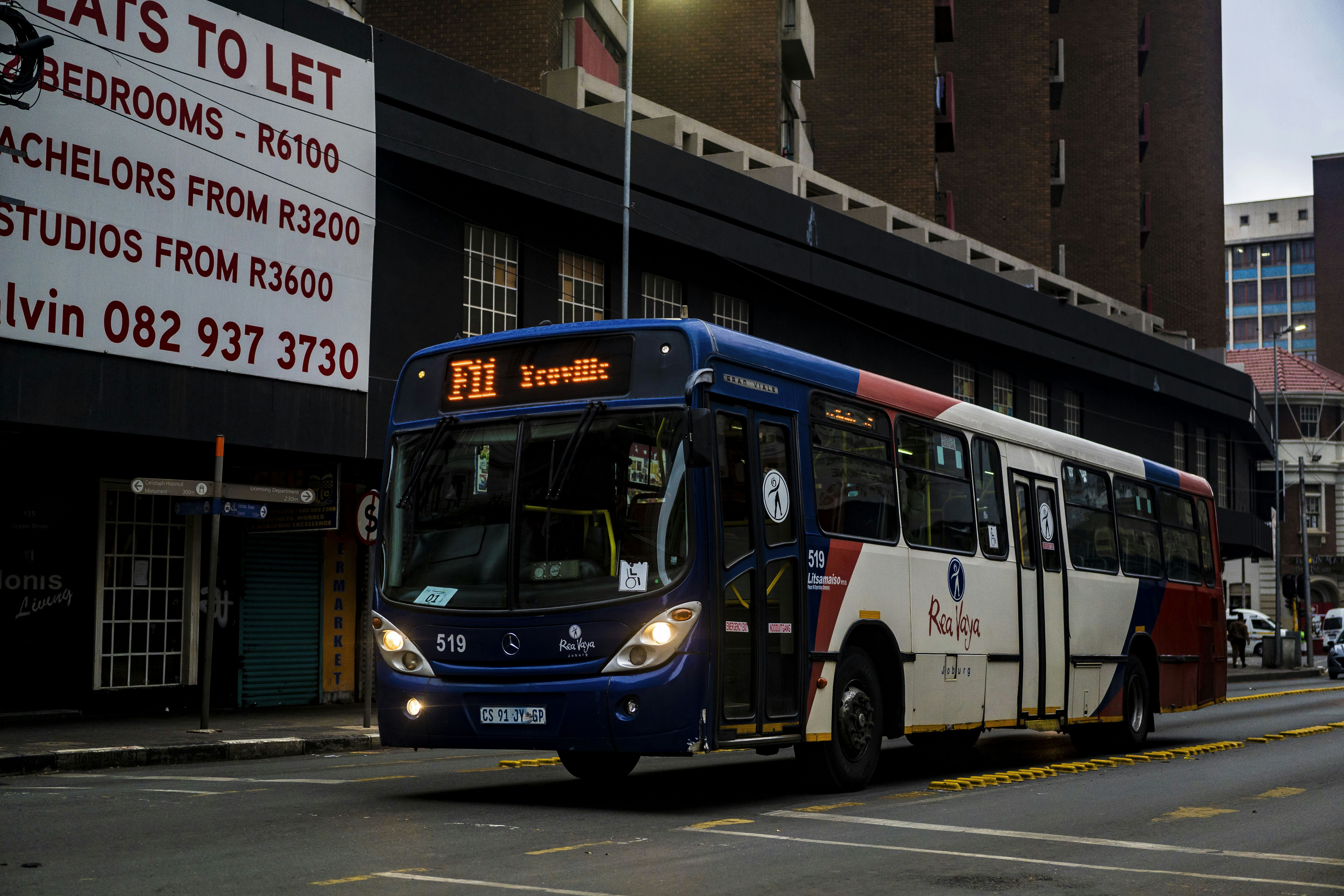 a blue and white bus driving down a street
