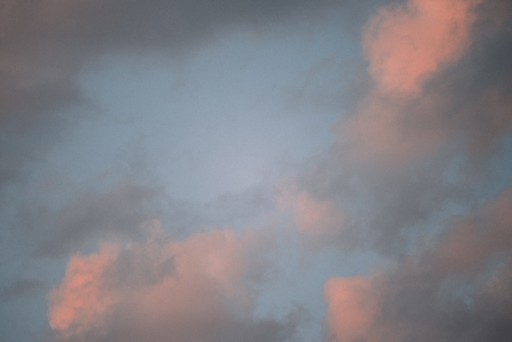 a plane flying through a cloudy sky at sunset