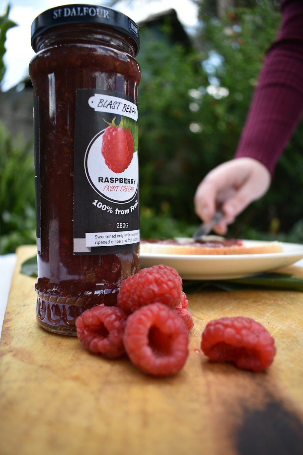 a jar of raspberry jam on a table with raspberries