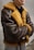 A person wearing a brown leather jacket with fur lining. The jacket has a classic aviator style and appears warm and cozy. The person stands with arms crossed, conveying a relaxed or confident demeanor.