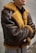 A person wearing a brown leather jacket with fur lining. The jacket has a classic aviator style and appears warm and cozy. The person stands with arms crossed, conveying a relaxed or confident demeanor.